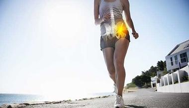 Woman with hip pain while walking on a trail.